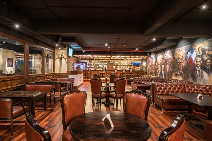 Round tables and leather booths in the indoor dining hall, beside a painted mural
